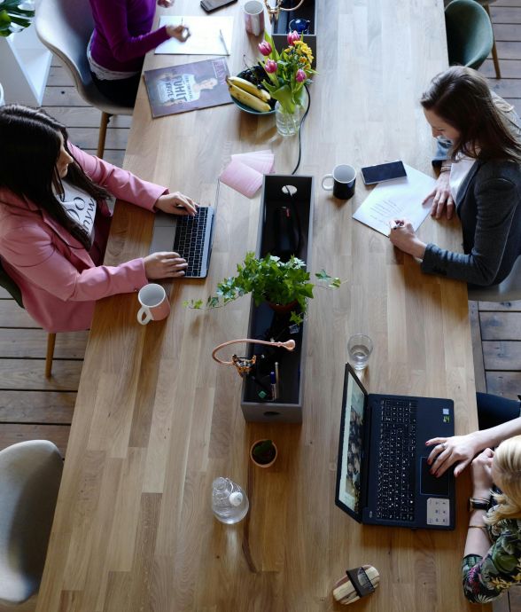 Overhead view of diverse women professionals working in a modern office setting, fostering collaboration and teamwork.